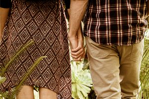 a man and a woman walking down a garden path holding hands romantically